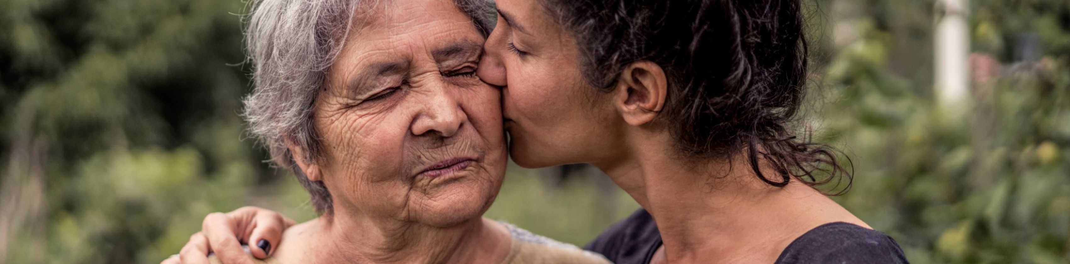 Ältere Dame mit jüngerer Dame, die ihr einen Kuss auf die Wange gibt, © Vladimir Borovic AdobeStock